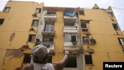 Maru Núñez, de 59 años, señala un edificio de viviendas dañado en la Misión Vivienda en Catia La Mar, Estado de La Guaira, Venezuela, el 12 de julio de 2026. REUTERS/Leonardo Fernández Viloria