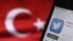 El logotipo de Twitter aparece en la pantalla de un móvil junto a una bandera turca.