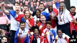 El equipo olímpico de judo francés, medallistas de oro por equipos mixtos, posan mientras celebran su regreso de los Juegos Olímpicos de Tokio 2020 frente a la Torre Eiffel, en París el 2 de agosto de 2021 (Foto de STEPHANE). DE SAKUTIN / AFP)