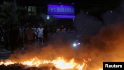 Manifestantes en Venezuela permanecen junto a una barricada en llamas en protesta por los cortes de electricidad. (REUTERS)