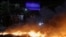 Manifestantes en Venezuela permanecen junto a una barricada en llamas en protesta por los cortes de electricidad. (REUTERS)