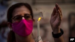 Una devota enciende una vela a la Virgen de la Caridad durante una misa en su honor transmitida por radio. (AP/Ramon Espinosa)