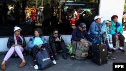 Cubanos esperan a sus compatriotas en las afueras de la Unidad de Flagrancia, en Quito, donde fueron procesados para la deportación. EFE