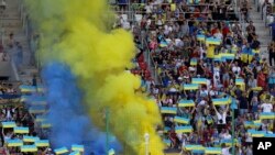 Hinchas de Ucrania vitorean en la grada durante un partido de la Liga de Naciones de la UEFA entre Ucrania y Armenia, en Lodz, Polonia, el sábado 11 de junio de 2022. (AP Foto/Michal Dyjuk)