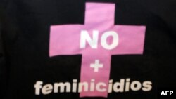 Una mujer sostiene una camisa con la frase "No mas Feminicidios "