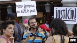 Participantes en la concentración en apoyo al grupo punk Pussy Riot, acusadas por cantar en una catedral ortodoxa una canción contra el presidente de Rusia, Vladimir Putin, sostiene una pancarta durante la manifestación que ha tenido lugar esta tarde en l