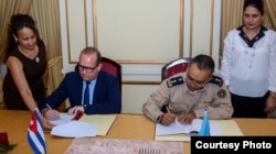 William Pérez González, vicejefe de la Aduana de Cuba, y Bob Van Den Bergher, representante de la ONUDD, firman un memorando para la inspección de contenedores.