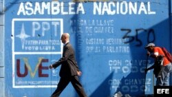 Un hombre pasa frente a un mural invitando a votar en las elecciones para elegir los diputados de la Asamblea Nacional. Foto de archivo.