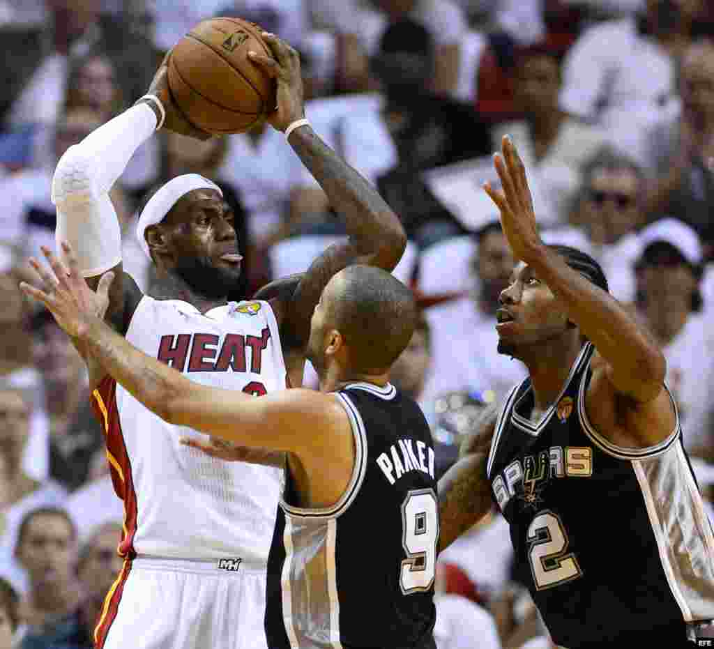 El jugador de Heat LeBron James (i) trata de pasar el balón ante la marca de Tony Parker (c) y Kawhi Leonard (d), de Spurs.