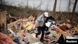 Dax Leandro rescata la ropa de los restos de la casa de su amigo, luego de que dos tornados seguidos tocaron tierra en Beauregard, Alabama.