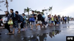 Varios supervivientes esperan en fila listos para abandonar la ciudad en Tacloban (Filipinas) el martes 12 de noviembre de 2013. 