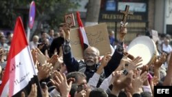 Un manifestante egipcio sostiene una cruz y un ejemplar del Corán durante una protesta organizada por la oposición en contra de Mohamed Mursi, en la céntrica plaza Tahrir de El Cairo, Egipto.