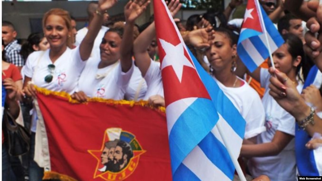 Jóvenes cubanos portan la bandera de la juventud comunista cubana.