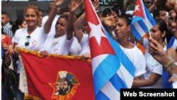 Jóvenes cubanos portan la bandera de la juventud comunista cubana.