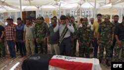 Miembros de la milicia chií Asaib Ahl al Haq (liga de los justos) rezan delante del ataúd de uno de sus compañeros, muerto en enfrentamientos con milicianos suníes, cerca de Samara, Nayaf, sur de Irak, hoy, viernes 20 de junio de 2014. 