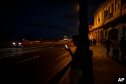 Foto Archivo. Una persona chequea su teléfono frente al Malecón de La Habana. AP Photo/Ramon Espinosa