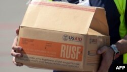Un hombre lleva una caja con paquetes con ayuda humanitaria traída por Estados Unidos para Venezuela.