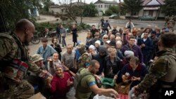 Efectivos ucranianos entregan suministros en el pueblo de Izium, Ucrania, el 2 de octubre de 2022. (AP/Evgeniy Maloletka).