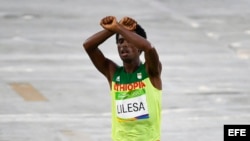 Feyisa Lilesa de Ethiopia levanta sus manos, como si estuviera esposado, en protesta.
