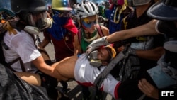 Un grupo de personas socorre a un manifestante herido tras enfrentarse a la policía durante una marcha antigubernamental en Caracas.