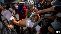 Un grupo de personas socorre a un manifestante herido tras enfrentarse a la policía durante una marcha antigubernamental en Caracas.