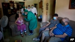 Técnicos de la salud realizan la prueba del coronavirus a una pareja en La Habana. (AP/Ismael Francisco)