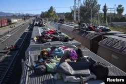 Los migrantes descansan en vagones de ferrocarril mientras esperan que un tren de carga viaje a la frontera con Estados Unidos, en un patio ferroviario en Chihuahua, México, 26 de diciembre de 2023. REUTERS/Raúl Fernando Pérez Lira