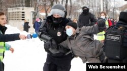 Un hombre vestido con un chaleco de prensa sostiene un micrófono mientras la policía lo detiene durante una manifestación en apoyo a Aleksei Navalny en San Petersburgo el 31 de enero de 2021.