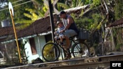 Un padre y su hijo montan en bicicleta por las vías del tren en el poblado de Guayacanes, en la provincia de Ciego de Ávila (Cuba). EFE/Alejandro Ernesto