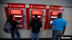 Personas extrayendo su dinero hoy en Caracas de los cajeros automáticos tras el anuncio del Gobierno de la devaluación del bolívar
