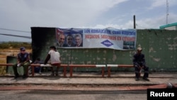 Trabajadores descansan junto a un cartel de Fidel Castro, Raúl Castro y Miguel Díaz-Canel, en la Base de Superpetroleros de Matanzas, Cuba, el 10 de agosto de 2022. REUTERS/Alexandre Meneghini