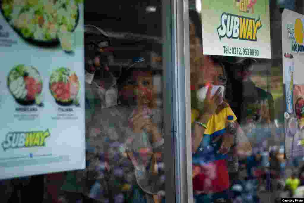 Manifestantes se resguardan en establecimiento de comida rápida Subway y observan el enfrentamiento entre manifestantes y efectivos de la PNB. (Foto: Juan Pablo Arraez) 