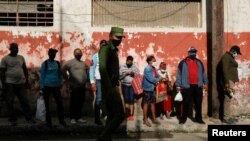 Un agente del MININT controla una cola en un mercado de La Habana. REUTERS/Stringer