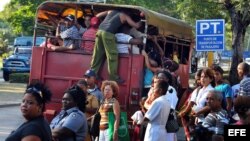  Varias personas suben a un camión de transporte de pasajeros en Santiago de Cuba.