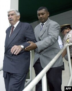 El cubano Luis Posada Carriles (I), auxiliado por un escolta salen de la sede del Tribunal Marítimo, al finalizar su primer día de juicio realizado en la Ciudad de Panamá, el 15 de marzo de 2004.