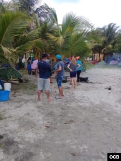 El grupo de cubanos en Necoclí acampa en la arena, con niños pequeños entre ellos.