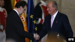 El Rey Juan Carlos estrecha la mano del presidente del Gobierno, Mariano Rajoy, tras firmar su abdicación.