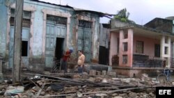Dos hombres limpian escombros en una casa que ha sido parcialmente destruida por el paso del huracán "Sandy", en la ciudad de Guantánamo (Cuba). 