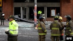  Bomberos y policías acuden a uno de los lugares de Bogotá donde estallaron el jueves sendos artefactos explosivos. Al menos ocho personas resultaron heridas. 