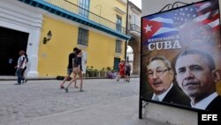 Transeúntes caminan cerca a una imagen de Barack Obama y Raúl Castro. #ObamaEnCuba.