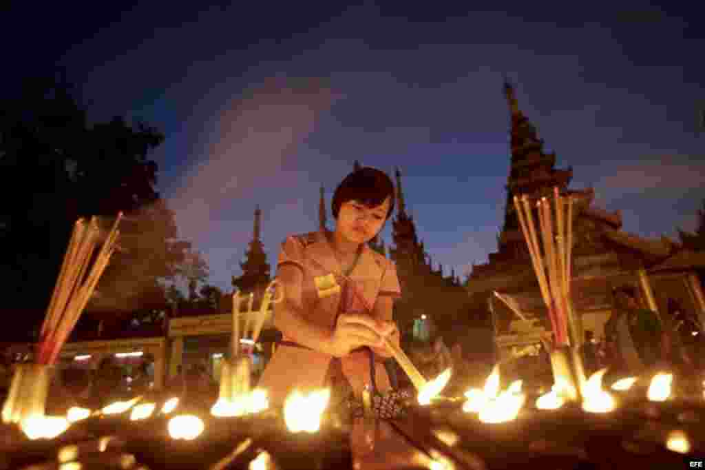Una fiel enciende una vela durante la primera noche del Año Nuevo en la padoga dorada de Shwedagon en Rangún, Birmania.