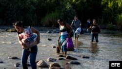 Un grupo de personas cruza el río Táchira, que divide a Venezuela y Colombia en el sector "La Invasión", en la ciudad de San Antonio (Venezuela)