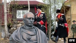 Cosacos rusos con su uniforme posan junto a busto de Putin. 