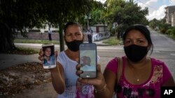 Servilia Pedroso (der.), madre del estudiante de 18 años Eloy Bárbaro Cardoso, y Yaquelin Cruz, madre de Dariel Cruz, dos manifestantes del 11J en La Güinera, muestran sus fotos. (AP/Ramón Espinosa) 