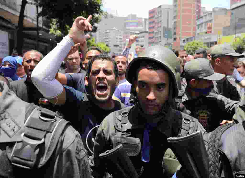 Un manifestante antigubernamental hace un gesto junto a miembros de la Guardia Nacional que se unieron a una marcha para apoyar al presidente interino Juan Guaidó, en Caracas.