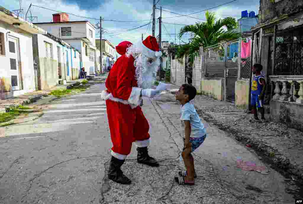 Un niño entrega una carta a un hombre vestido de Papá Noel en una calle de La Habana el 21 de diciembre de 2023. (Foto de Yamil LAGE / AFP)