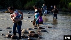 Un grupo de personas cruza el río Táchira, que divide a Venezuela y Colombia en el sector "La Invasión", en la ciudad de San Antonio (Venezuela)