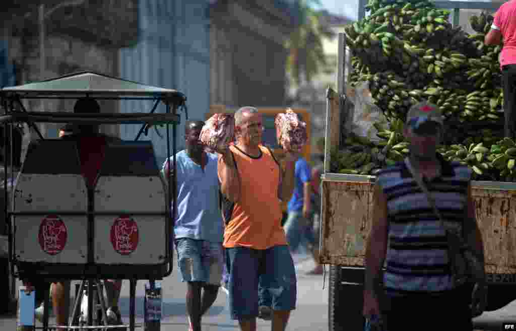 Un hombre camina con dos pedazos de carne hoy, jueves 17 de marzo, por una calle de La Habana