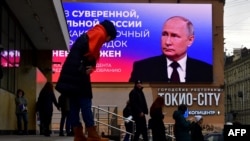 La imagen del presidente ruso Vladimir Putin se despliega en una pantalla digital junto a una cita de su reciente discurso ante la Asamblea Federal, en San Petersburgo. (Olga Maltseva/AFP)