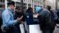 Un policía pide a los vendedores ambulantes que le muestren sus permisos para vender en la calle.